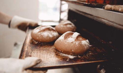 baker-pulls-out-of-the-oven-a-baking-sheet-the-bak-2023-11-27-05-14-11-utc